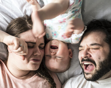 Schreiendes Baby mit Eltern als Symbol für Elternsex